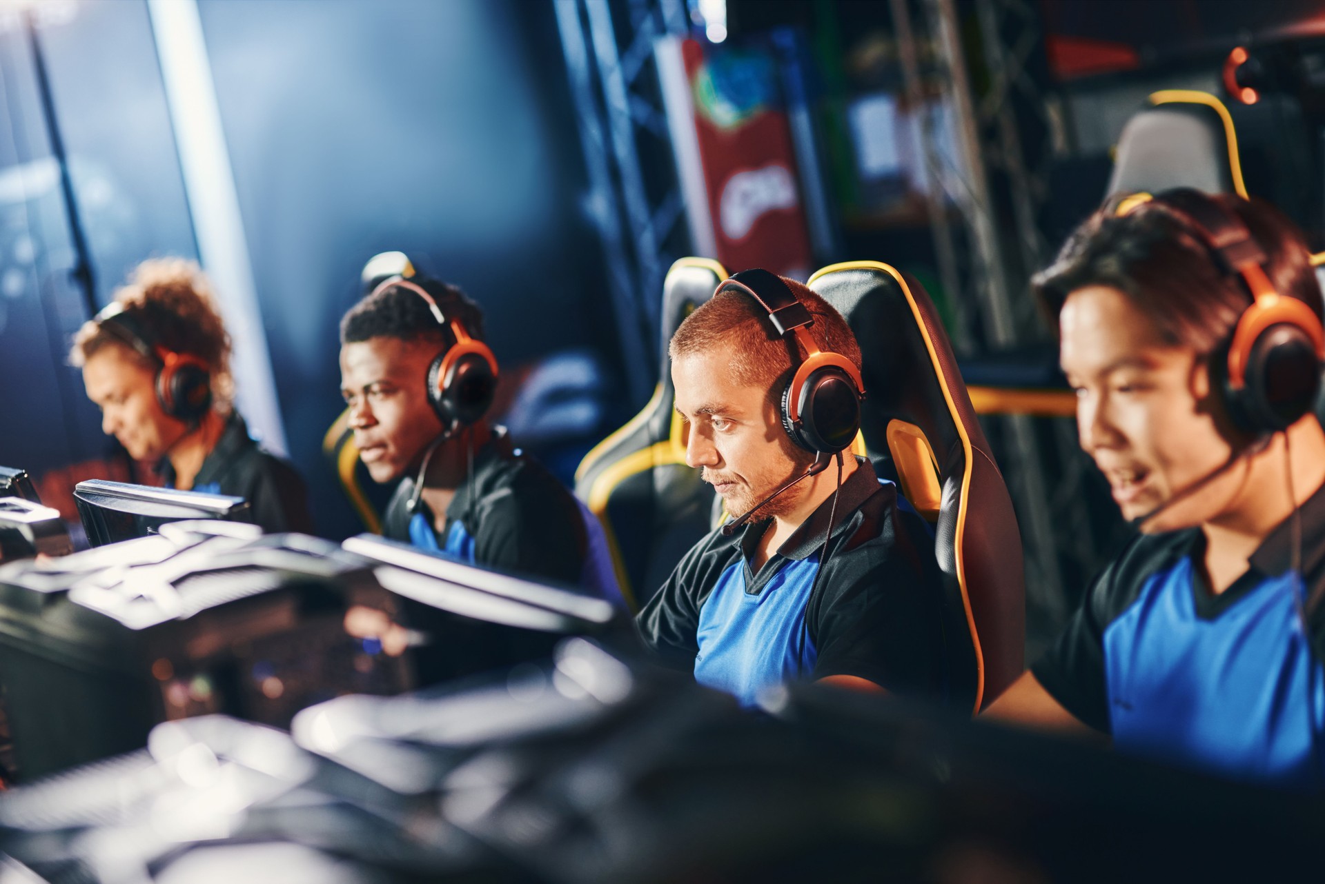 Equipo de cuatro jugadores profesionales de ciberdeporte que usan auriculares que participan en el torneo de eSport, jugando videojuegos en línea